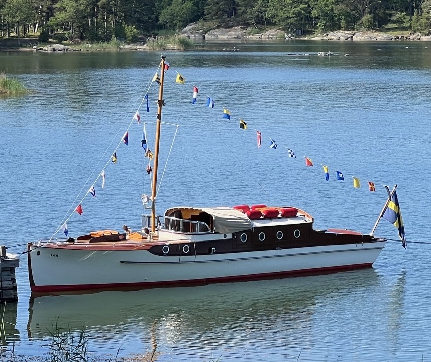 m/y IAN 1928 flaggad över topp i Stockholms skärgård